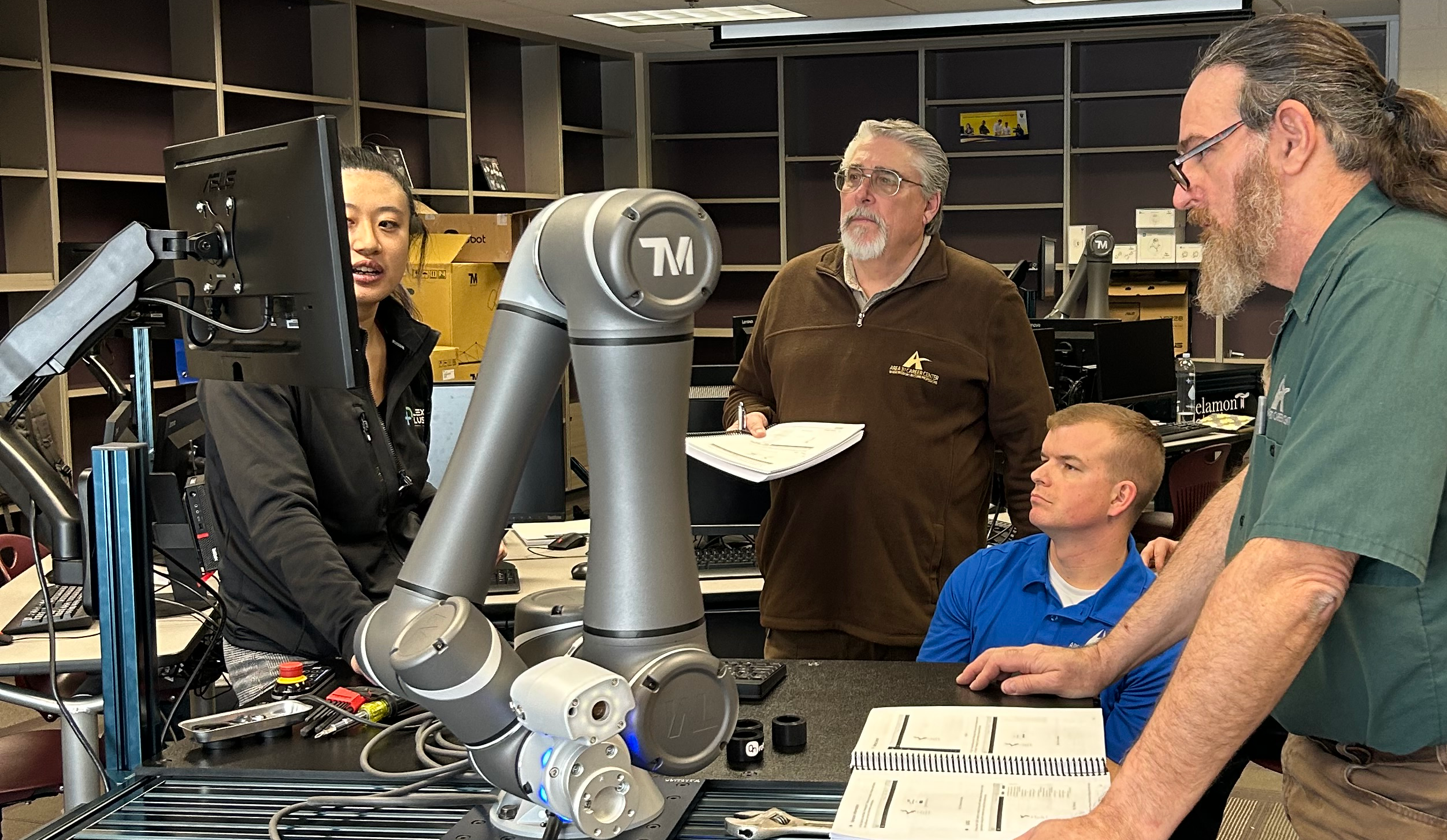 A female conducts cobot training as 3 men look on.