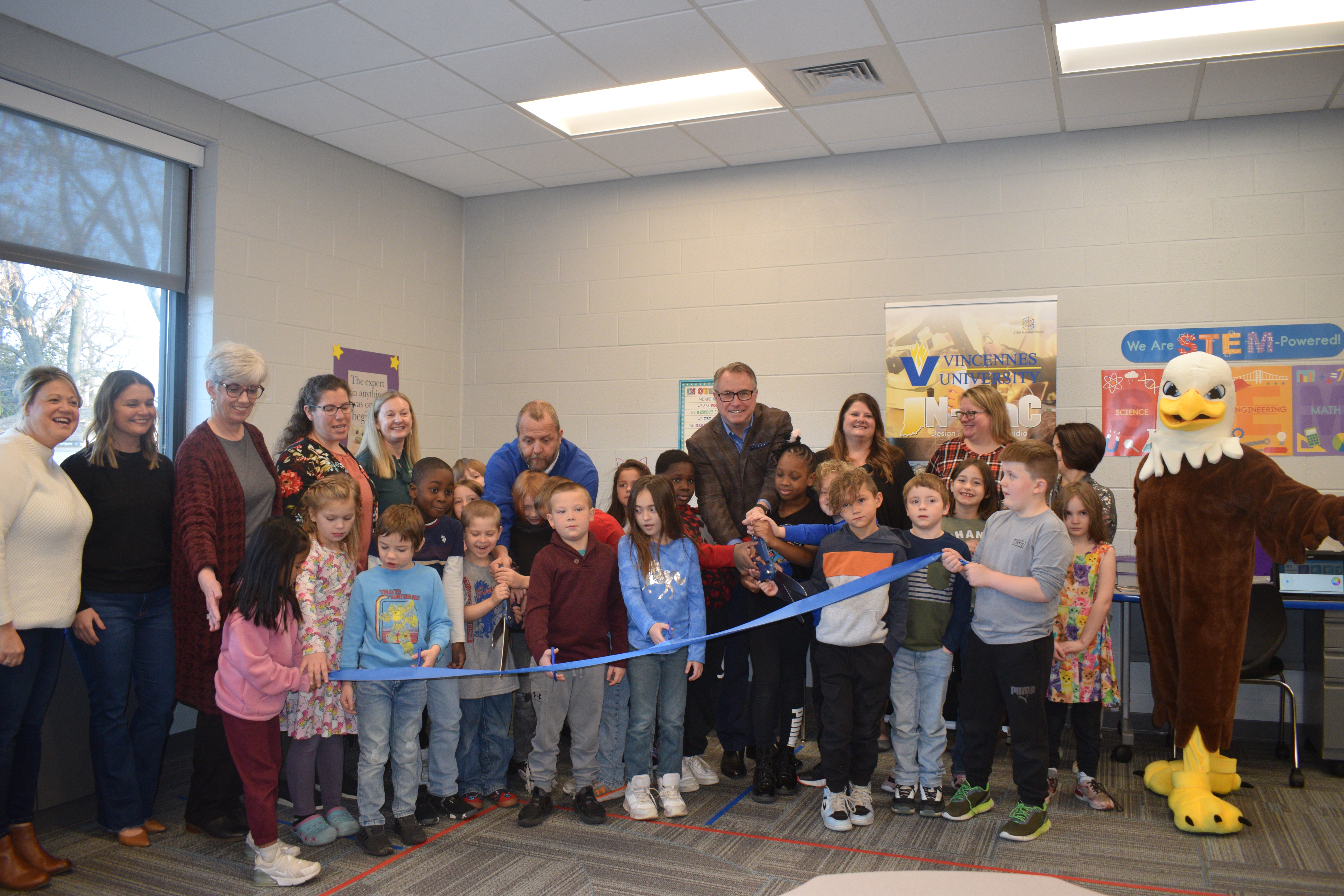 Tecumseh-Harrison Elementary School students and staff, VU leaders, and Purdue IN-MaC leaders cut a blue ribbon to commemorate the new Design and Innovation Studio at Tecumseh-Harrison school. 